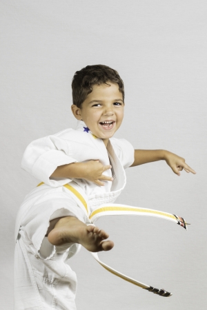 A young boy jumping and kicking dressed in a karate uniform の写真素材