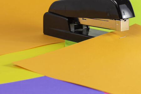 A black stapler fastening colorful pages.の写真素材