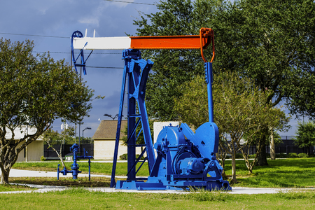 A red white and blue nodding donkey pumpjack used for taking oil from the ground.の写真素材