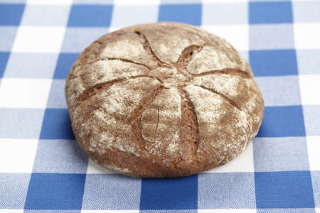 A loaf of bread on a blue-white checkered tablecloth.の写真素材