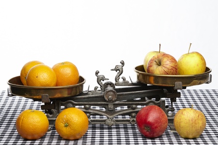 Apples and oranges on an old balance to visualisize the saw to compare apples to oranges.の写真素材