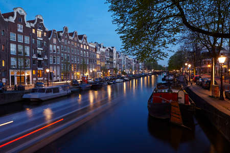 Canal in Amsterdam in the evening with some old houses and the brunches of a tree. のeditorial素材
