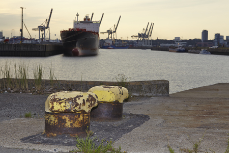 Old bollards at the Ellerholz Port in Hamburg (Germany) taken with light contre-jour in front of a...