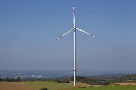 An open landscape with wind turbine taken at sunlight in front of a cloudless blue sky.