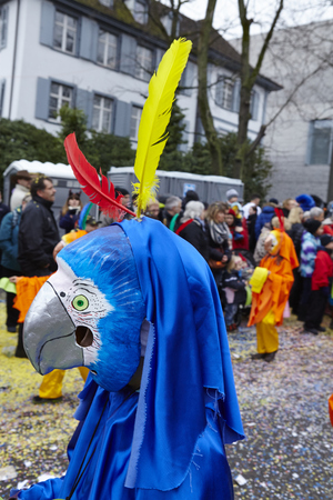 A fully costumed carnival activist walks through the city during the carnival procession (cortege) of the Carnivel at Basel 2016 (Basle - Switzerland) on February 15, 2016. Some unidentified visitors watching the procession from the edge of the road.のeditorial素材