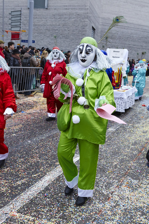 A fully costumed carnival activist walks through the city during the carnival procession (cortege) of the Carnivel at Basel 2016 (Basle - Switzerland) on February 15, 2016. Some unidentified visitors watching the procession from the edge of the road.のeditorial素材