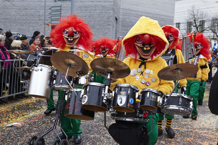 Some fully costumed carnival activists walk through the city during the carnival procession (cortege) of the Carnivel at Basel 2016 (Basle - Switzerland) on February 15, 2016. Some unidentified visitors watching the procession from the edge of the road.のeditorial素材