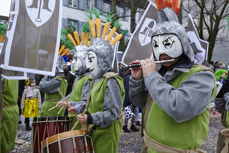 Some fully costumed carnival activists walk through the city during the carnival procession (cortege) of the Carnivel at Basel 2016 (Basle - Switzerland) on February 15, 2016. Some unidentified visitors watching the procession from the edge of the road.のeditorial素材