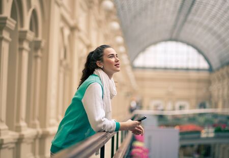 woman dreaming, looking up with smartphone in her handsの写真素材