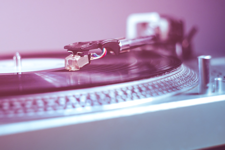 close up photo of vinyl turntable in colorfully light