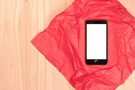 top view of smartphone on red paper on wooden surfaceの写真素材