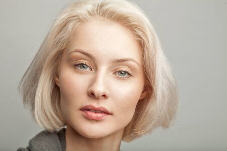 Photo close up portrait of young attractive blonde caucasian woman in gray t-shirt on gray...