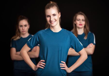Team leader with two players of women football team on black background