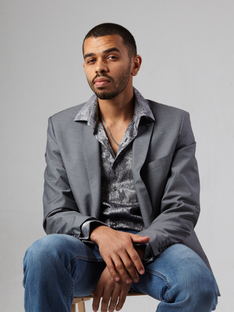 attractive young black man in gray blazer isolated on studio gray backgroundの写真素材
