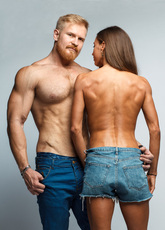 caucasian couple topless woman and brutal man with beard in jeans isolated on studio backgroundの写真素材