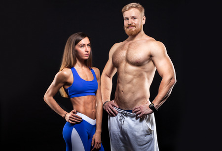 young  caucasian muscular male with sexy female with athletic body isolated on black backgroundの写真素材