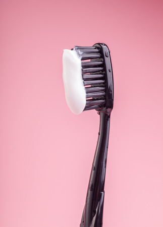 black toothbrush with white toothpaste isolated on bright pink backgroundの写真素材