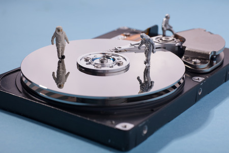 toy figures of men in anti radiation suits on surface of hard drive disk explore IT risk and...