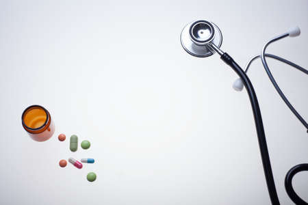 various medicine drugs and pills with stethoscope on medical light table, flat lay template, center copy-spaceの写真素材