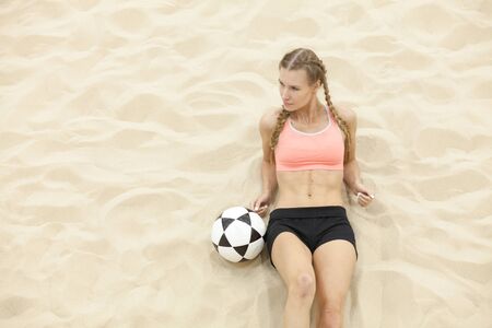 young sportswoman with ball lay on sandの写真素材
