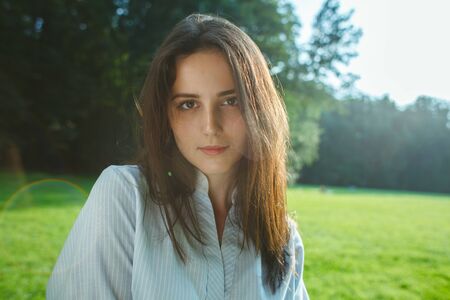 close up portrait of attractive brunette female on nature background at sunny dayの写真素材