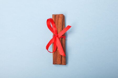 cinnamon bandaged with red ribbon isolated on blue background