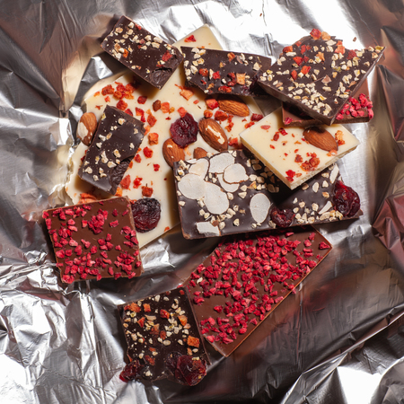 many different pieces of chocolate with topping in foilの写真素材