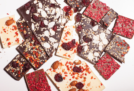 many different pieces of chocolate with topping isolated on white background