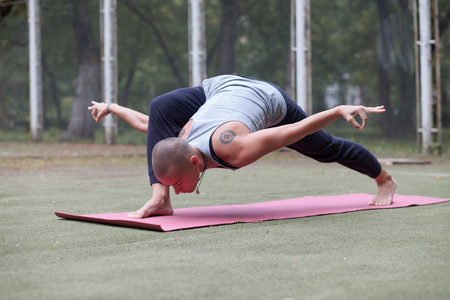 young tranquil woman doing high yoga lunge outdoor in summer parkの写真素材