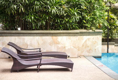 two empty chaise lounges near pool and tropic palms