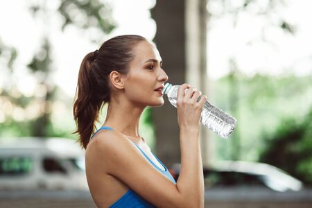 close up portrait of fitness smiling woman drinking water on street outdoor workout in city