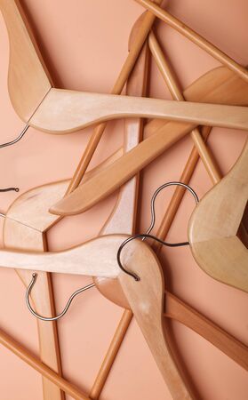 many beige wooden coat hangers randomly placed on brown background, pattern, texture, vertical shot