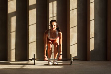 athletic woman doing dead lift exercise with barbell in gymの写真素材