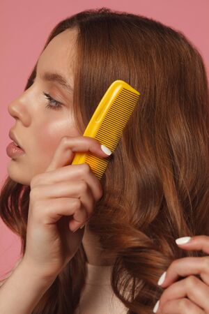 pretty girl combing her hair with combの写真素材