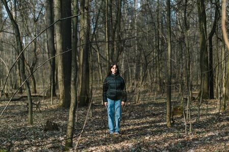 Young woman standing alone in wild forest, self-isolation loneliness conceptの写真素材