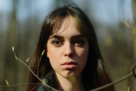 close up portrait of young pretty woman between tree branchesの写真素材