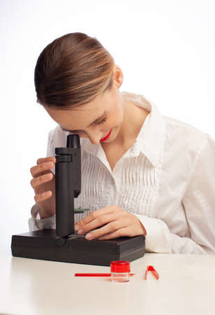 young female student using microscope in science laboratory