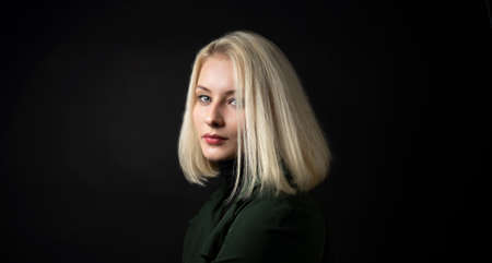 close up of pale blonde woman isolated on dark background