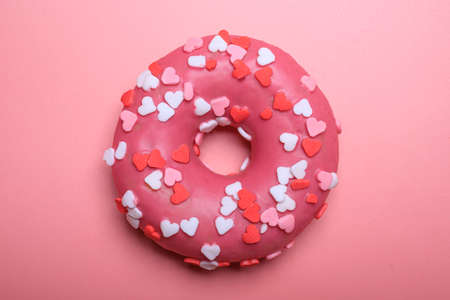 one tasty donut with pink glaze and heart shape sprinkles isolated on pink backgroundの写真素材