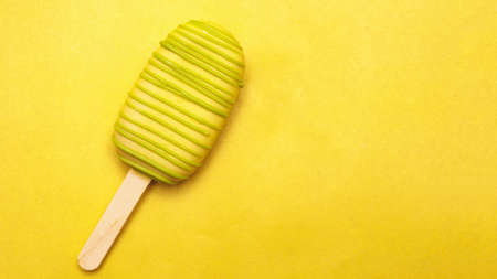 ice cream on stick, yellow chocolate glaze isolated on yellow background, copy space rightの写真素材