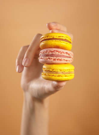 hand holding stacked different macaroons isolated on brown backgroundの写真素材