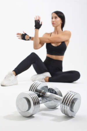 steel dumbbells on front near blurred sportswoman warming up arms before workout isolated on white background, selective focusの写真素材