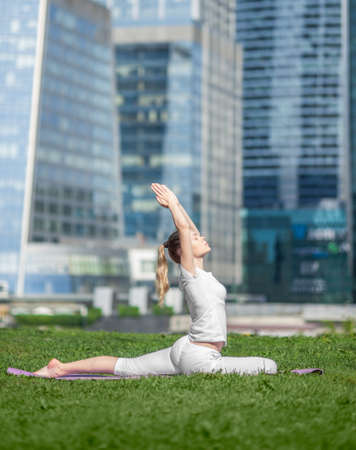 young caucasian woman doing yoga on the skyscraper backgroundの写真素材