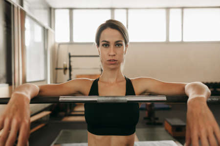 athletic woman standing in barbell rack in oldschool fitness gym