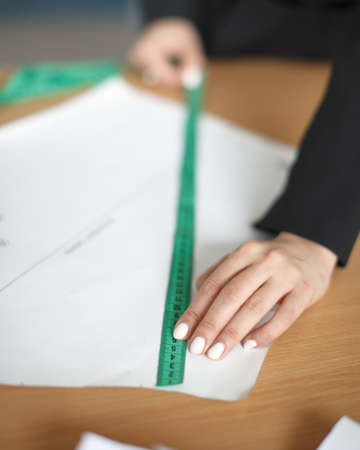 Female hands using measuring ribbon to sewing pattern, selective focusの写真素材