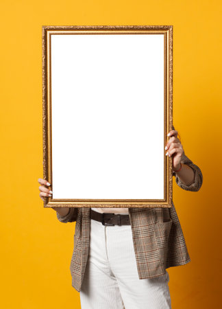 female with blank white picture frame isolated on yellow background, template mock upの写真素材