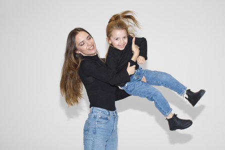 joyful mother and daughter having fun together. mom playfully lifts her child, both laughing and...