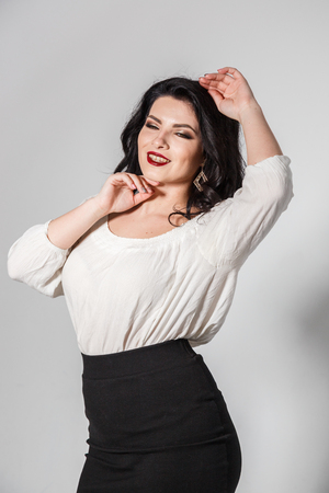 Beautiful brunette girl in skirt and blouse posing on white backgroundの写真素材