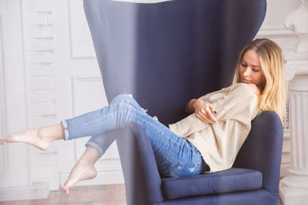 Beautiful sexy girl blonde in jeans posing in the morning in the apartment room, bright roomの写真素材