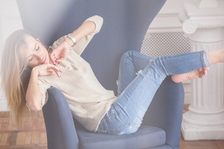 Beautiful sexy girl blonde in jeans posing in the morning in the apartment room, bright roomの写真素材